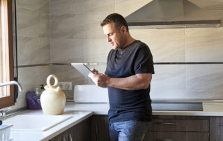 a Texas home inspector completes an inspection report using his tablet while inspecting the modern kitchen of a home